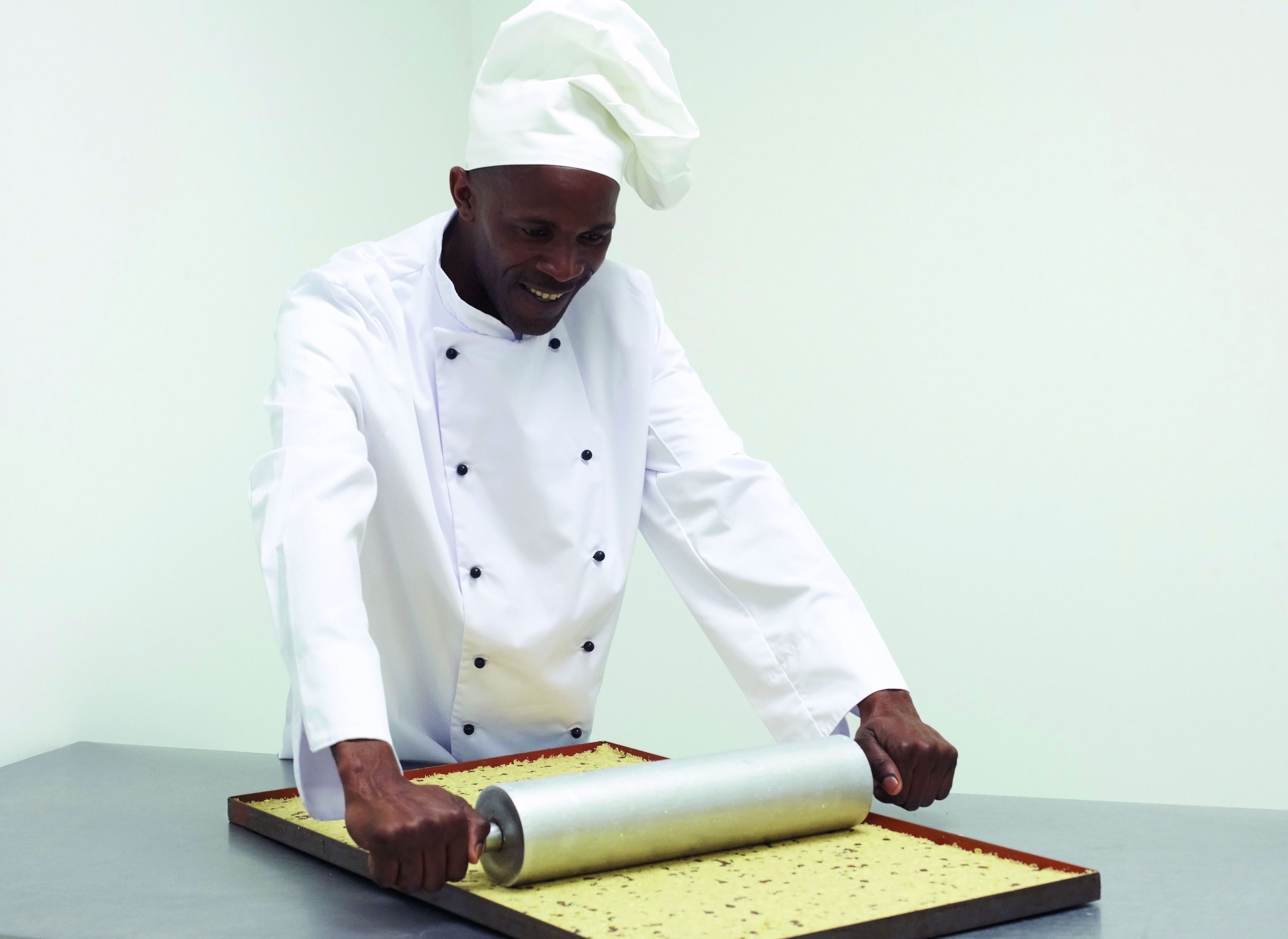 Master baker at The Cookie Factory rolling biscuit dough